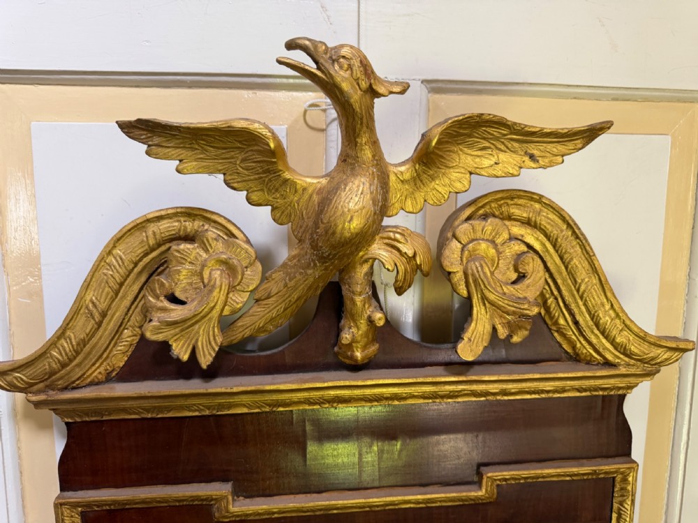 A nineteenth-century George II revival mahogany pier mirror featuring parcel-gilt mouldings, side foliage carvings, a broken pediment, and a carved eagle finial. View IV