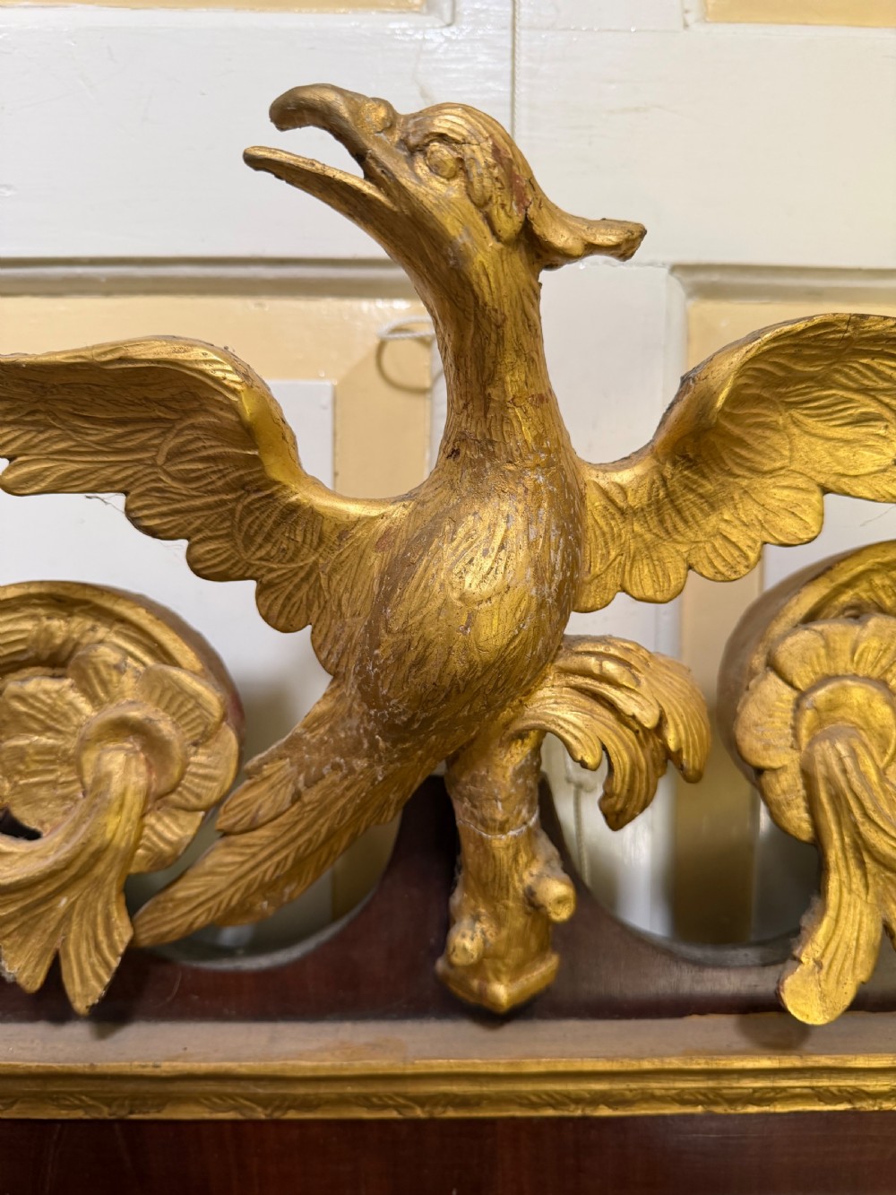 A nineteenth-century George II revival mahogany pier mirror featuring parcel-gilt mouldings, side foliage carvings, a broken pediment, and a carved eagle finial. View VII