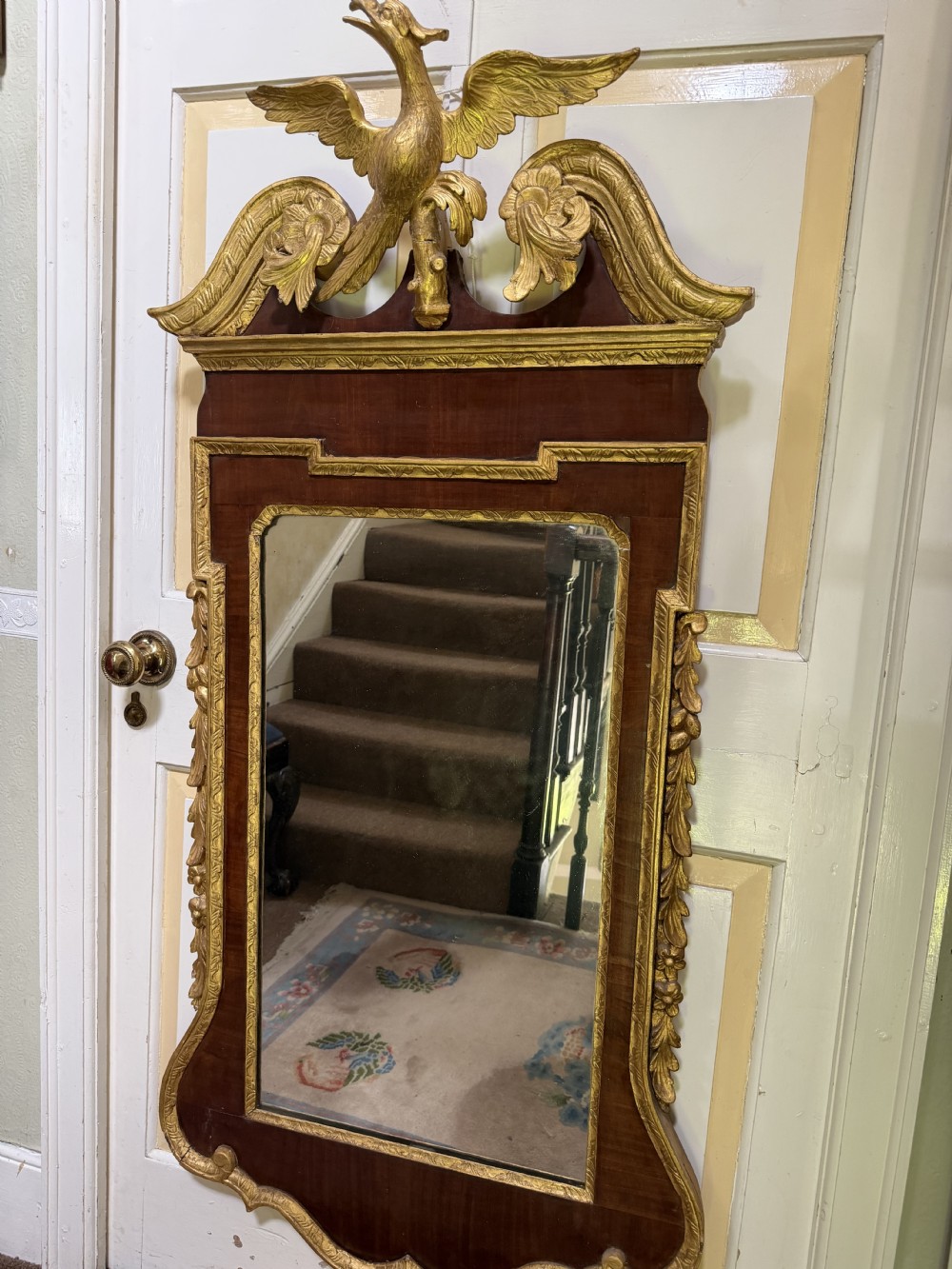 A nineteenth-century George II revival mahogany pier mirror featuring parcel-gilt mouldings, side foliage carvings, a broken pediment, and a carved eagle finial. View XII
