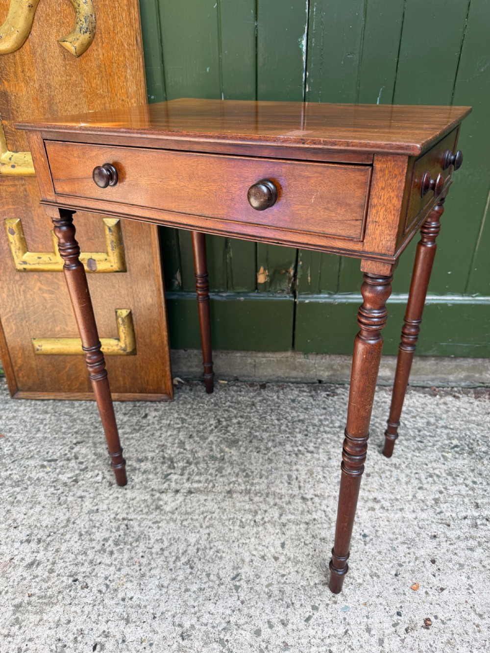 An early 19th-century George III period rectangular mahogany side table featuring a single drawer with turned wood handles and slender ring-turned legs.