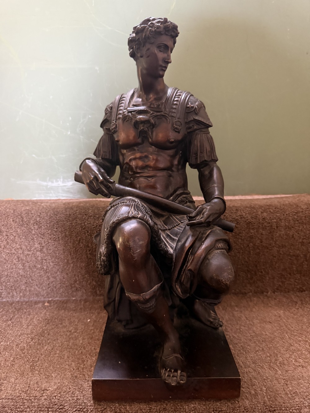 A pair of patinated dark bronze sculptures depicting two seated male figures in classical Roman armour mounted on rectangular bases. View III