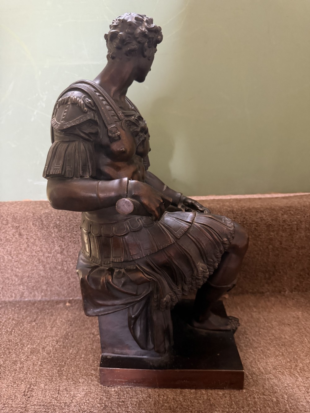 A pair of patinated dark bronze sculptures depicting two seated male figures in classical Roman armour mounted on rectangular bases. View VI