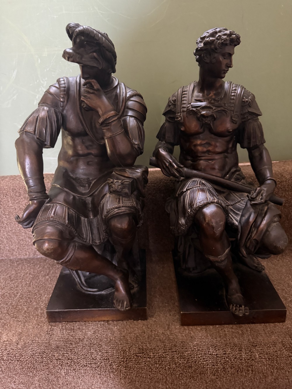 A pair of patinated dark bronze sculptures depicting two seated male figures in classical Roman armour mounted on rectangular bases. View XIII
