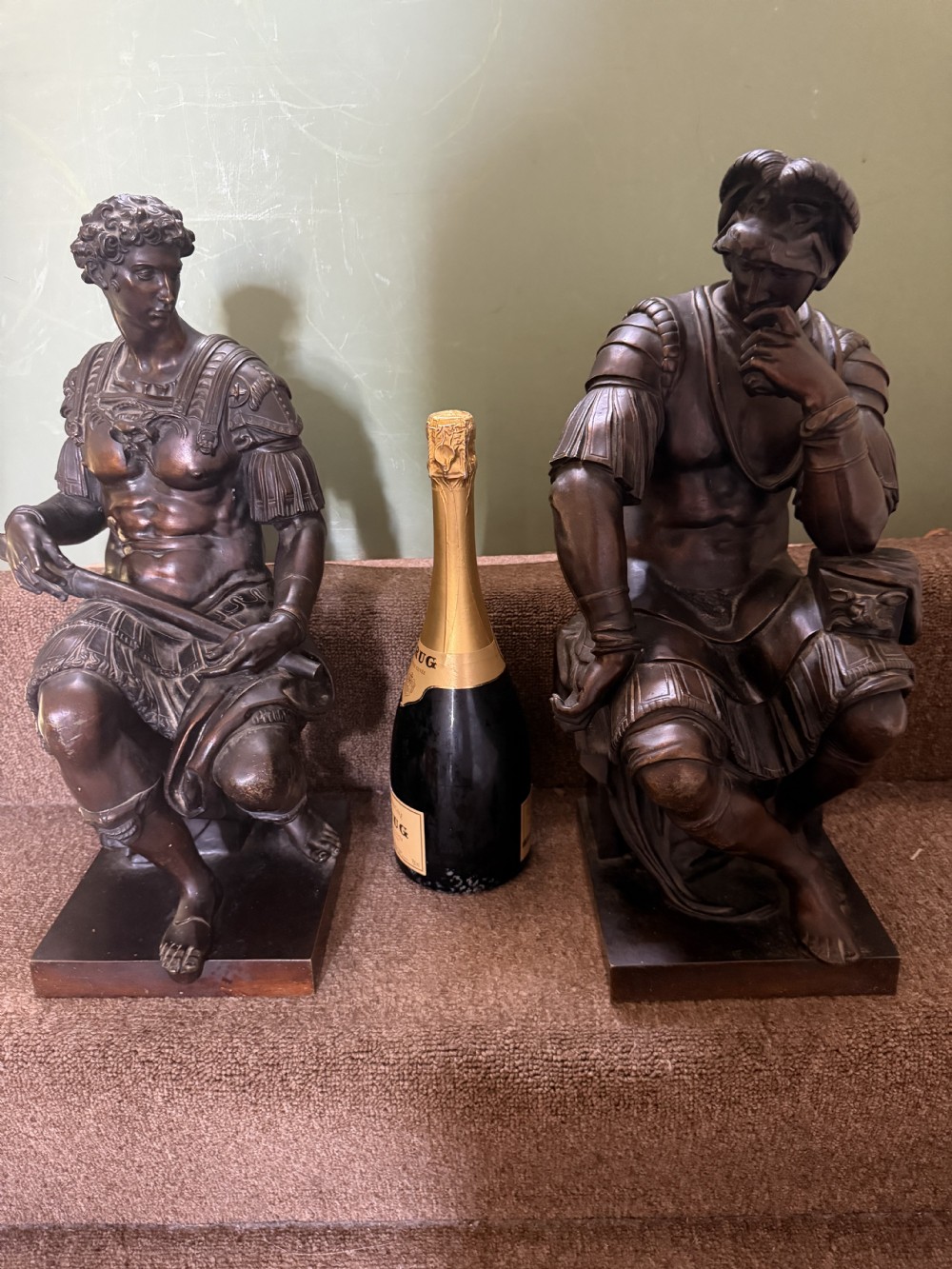 A pair of patinated dark bronze sculptures depicting two seated male figures in classical Roman armour mounted on rectangular bases. View XIV