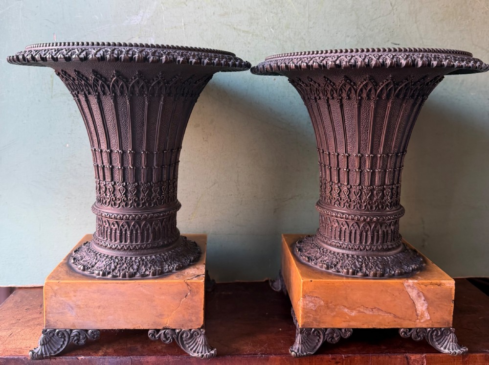 A pair of early nineteenth-century French bronze flared urns with Gothic tracery detailing, set upon square yellow Siena marble plinth bases with bronze bracket feet. View II