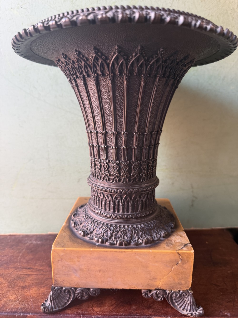 A pair of early nineteenth-century French bronze flared urns with Gothic tracery detailing, set upon square yellow Siena marble plinth bases with bronze bracket feet. View X