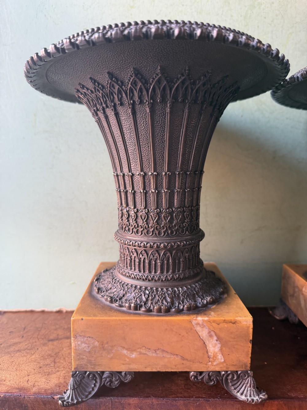 A pair of early nineteenth-century French bronze flared urns with Gothic tracery detailing, set upon square yellow Siena marble plinth bases with bronze bracket feet. View XIII