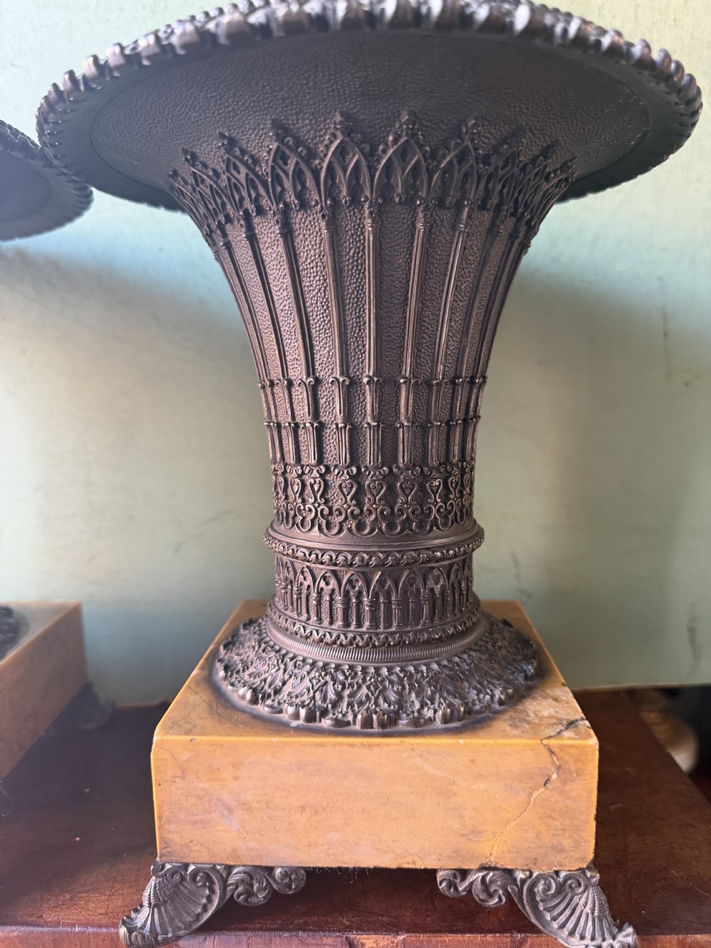 A pair of early nineteenth-century French bronze flared urns with Gothic tracery detailing, set upon square yellow Siena marble plinth bases with bronze bracket feet. View XIV