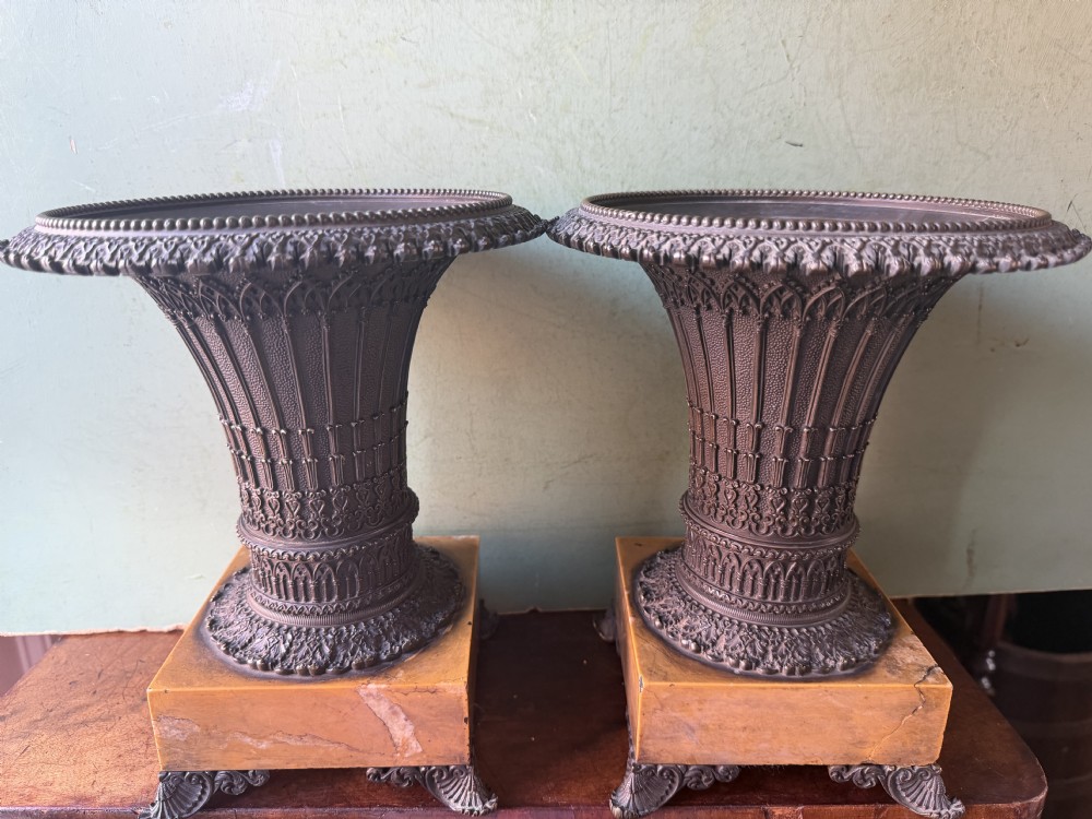 A pair of early nineteenth-century French bronze flared urns with Gothic tracery detailing, set upon square yellow Siena marble plinth bases with bronze bracket feet. View XV