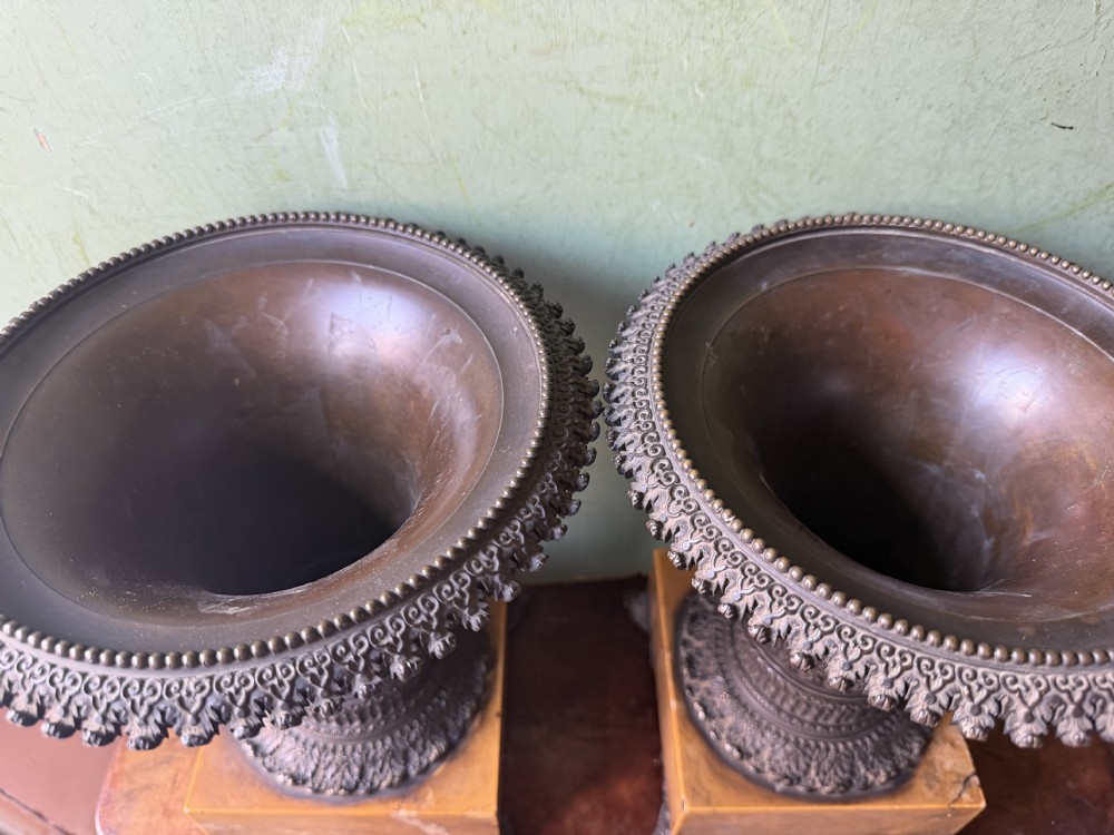A pair of early nineteenth-century French bronze flared urns with Gothic tracery detailing, set upon square yellow Siena marble plinth bases with bronze bracket feet. View XIX