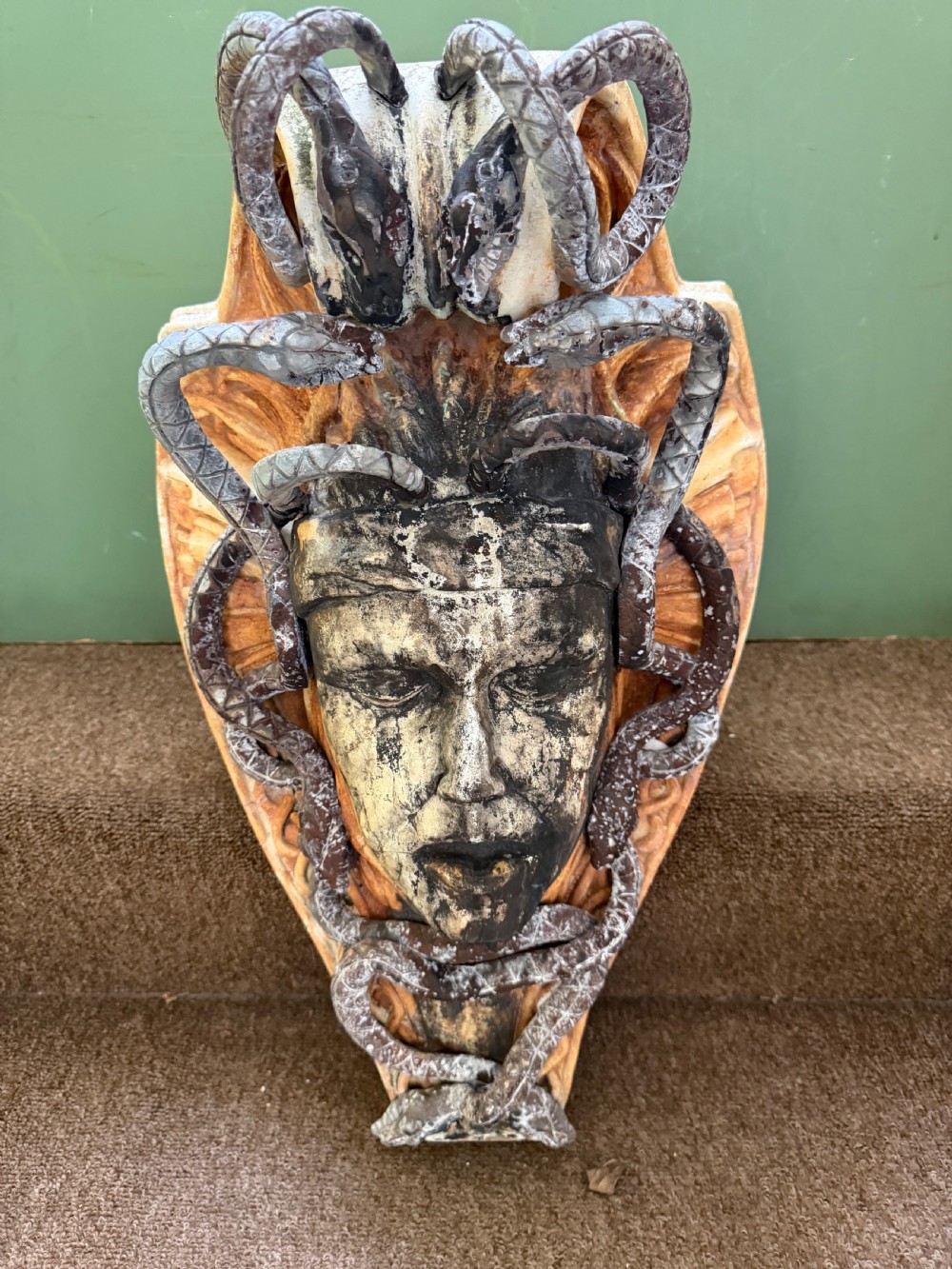 A carved stone wall bracket featuring a central Medusa head motif surrounded by lead-formed serpents against an arched background. View II