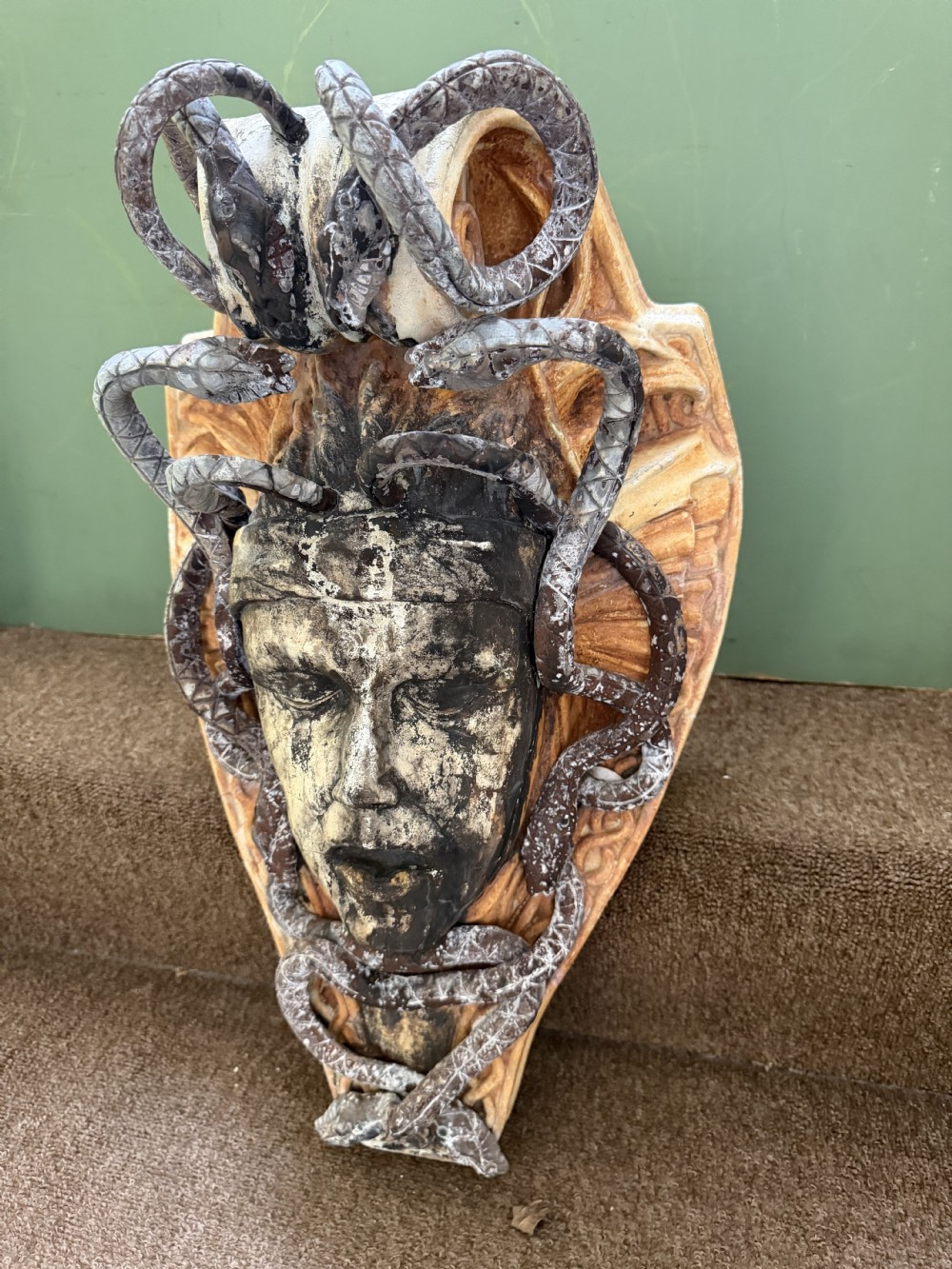 A carved stone wall bracket featuring a central Medusa head motif surrounded by lead-formed serpents against an arched background. View IV