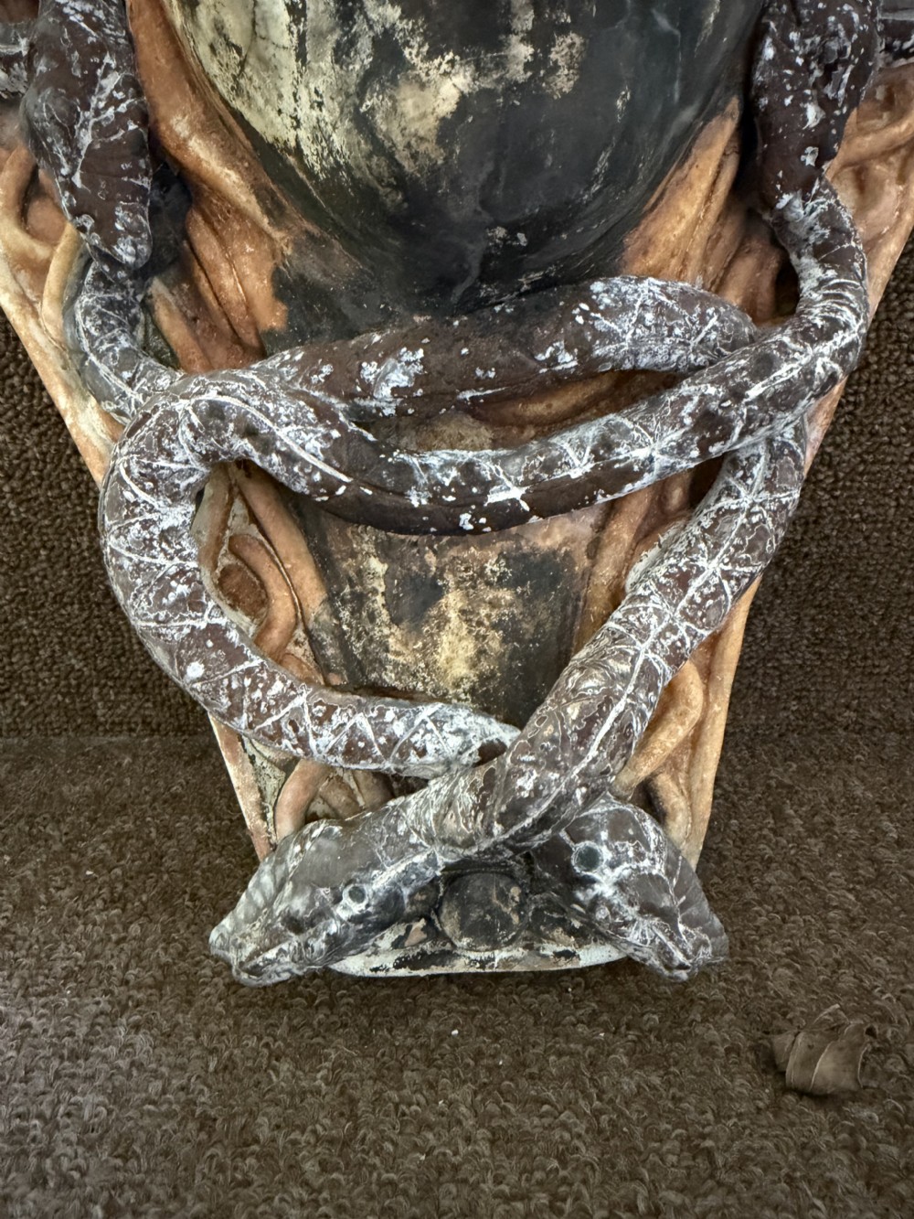 A carved stone wall bracket featuring a central Medusa head motif surrounded by lead-formed serpents against an arched background. View VI