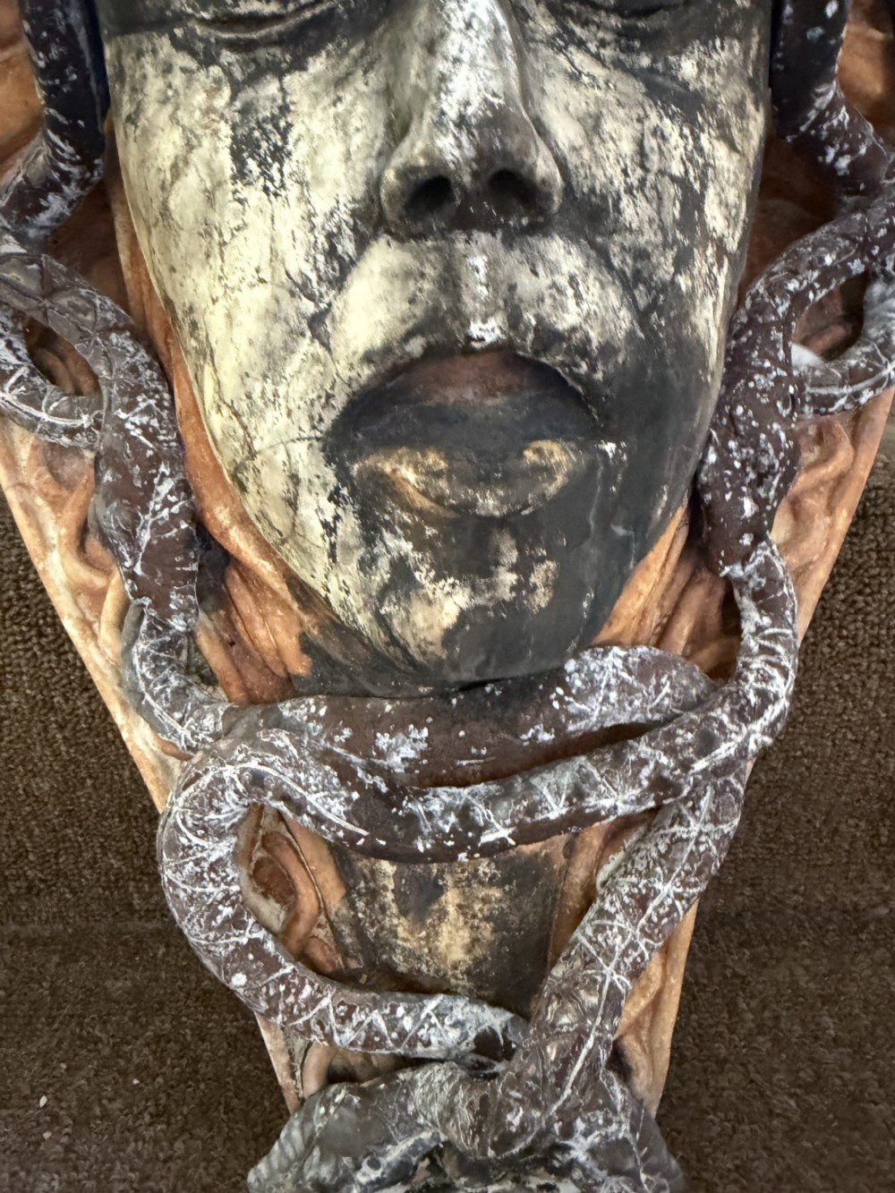 A carved stone wall bracket featuring a central Medusa head motif surrounded by lead-formed serpents against an arched background. View VII