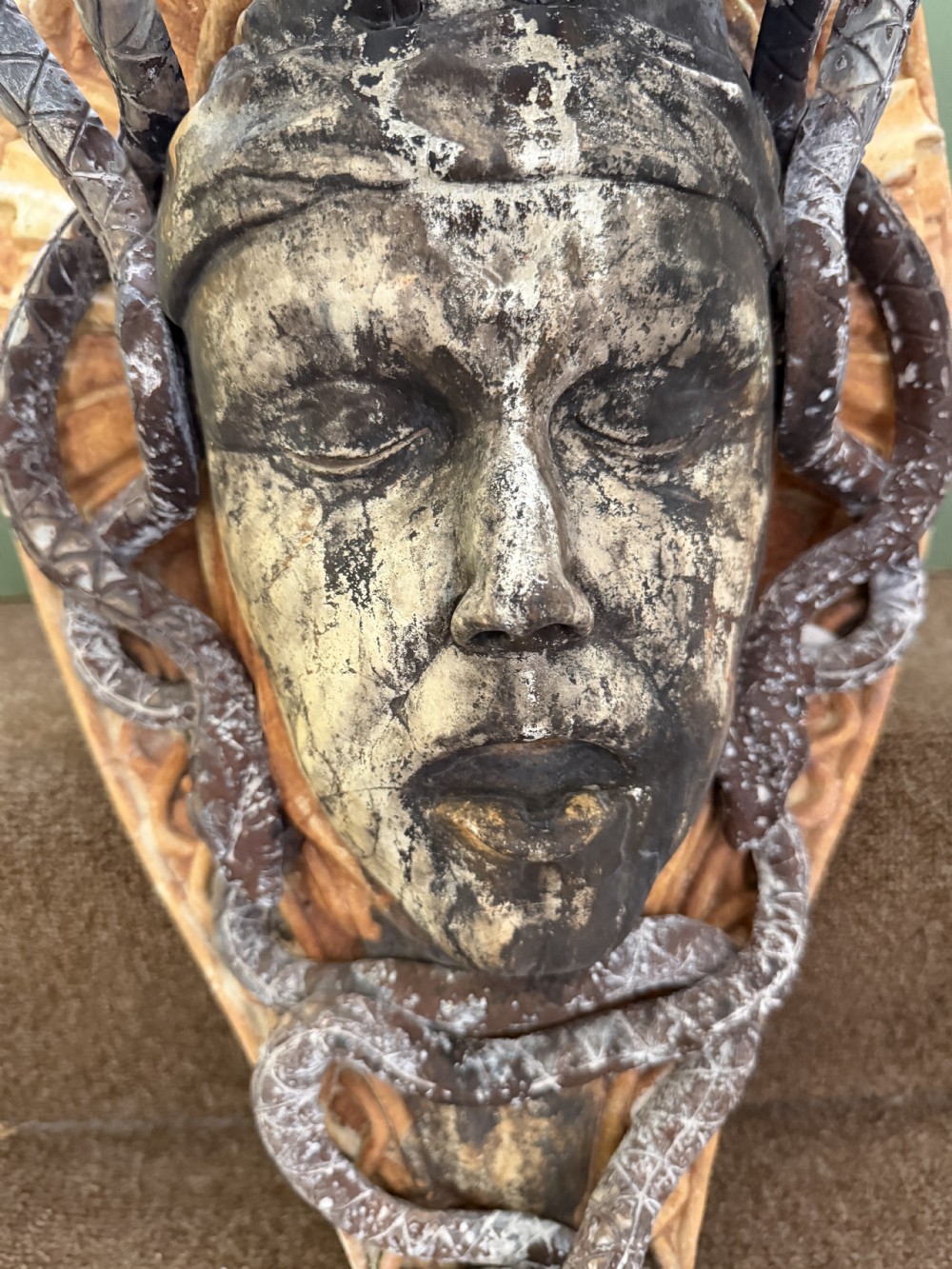 A carved stone wall bracket featuring a central Medusa head motif surrounded by lead-formed serpents against an arched background. View VIII