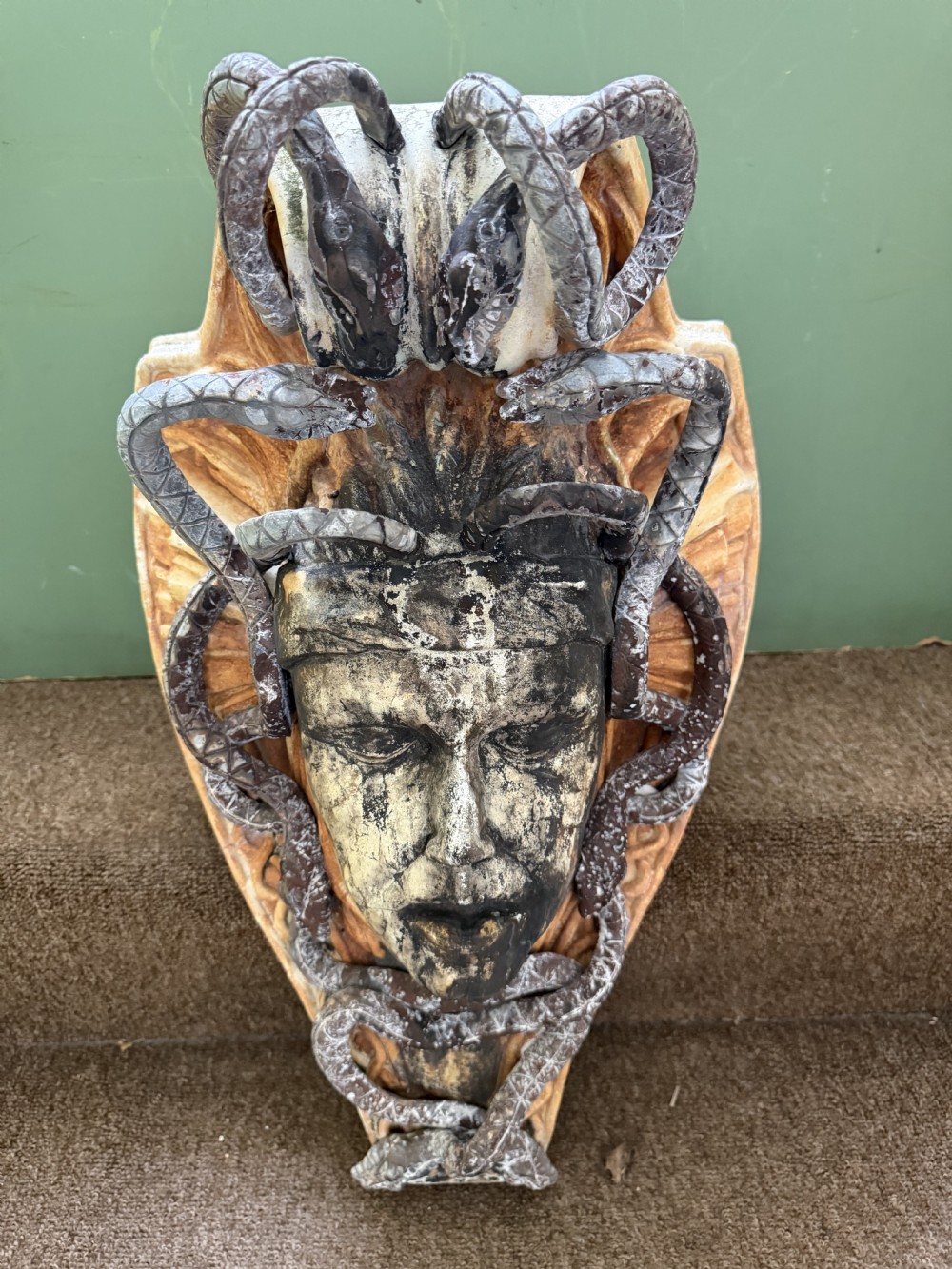 A carved stone wall bracket featuring a central Medusa head motif surrounded by lead-formed serpents against an arched background. View XI