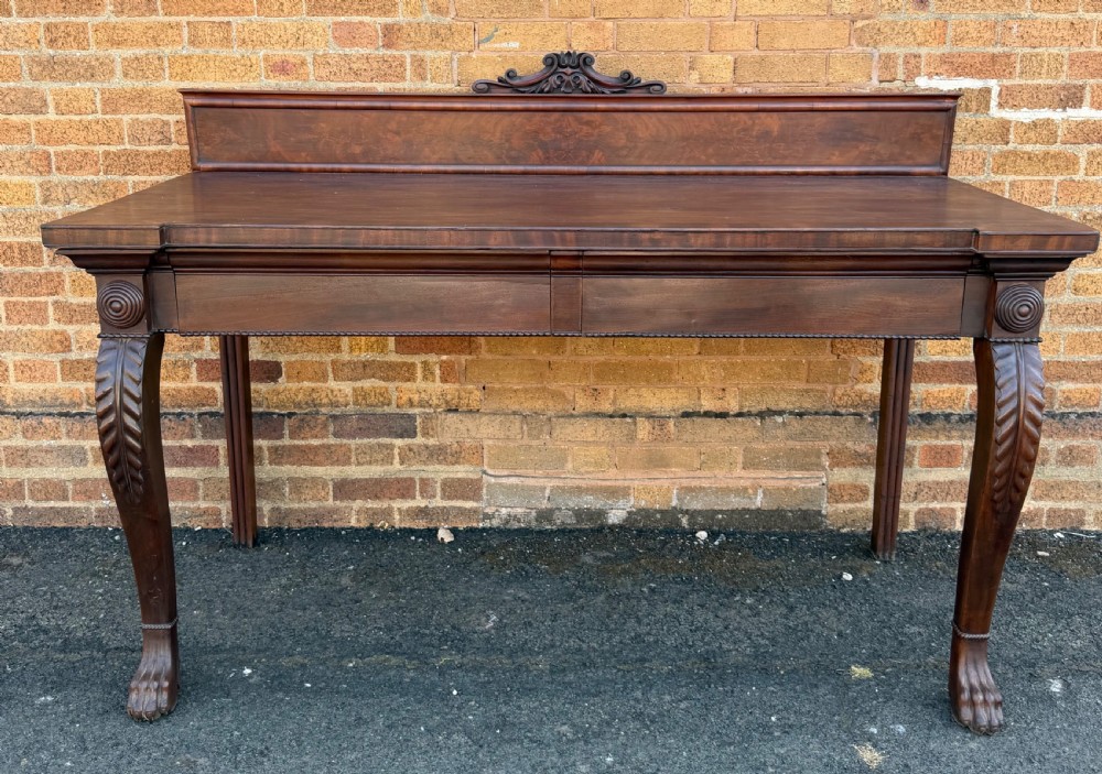 A large early 19th-century George IV mahogany serving table featuring a raised gallery back with carved cresting, carved cabriole front legs, and lion paw feet.