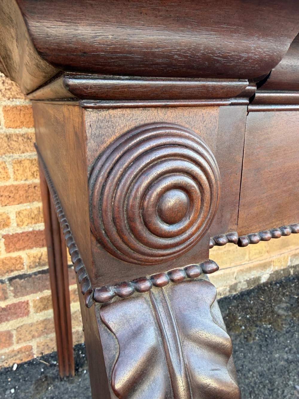 A large early 19th-century George IV mahogany serving table featuring a raised gallery back with carved cresting, carved cabriole front legs, and lion paw feet. View IV