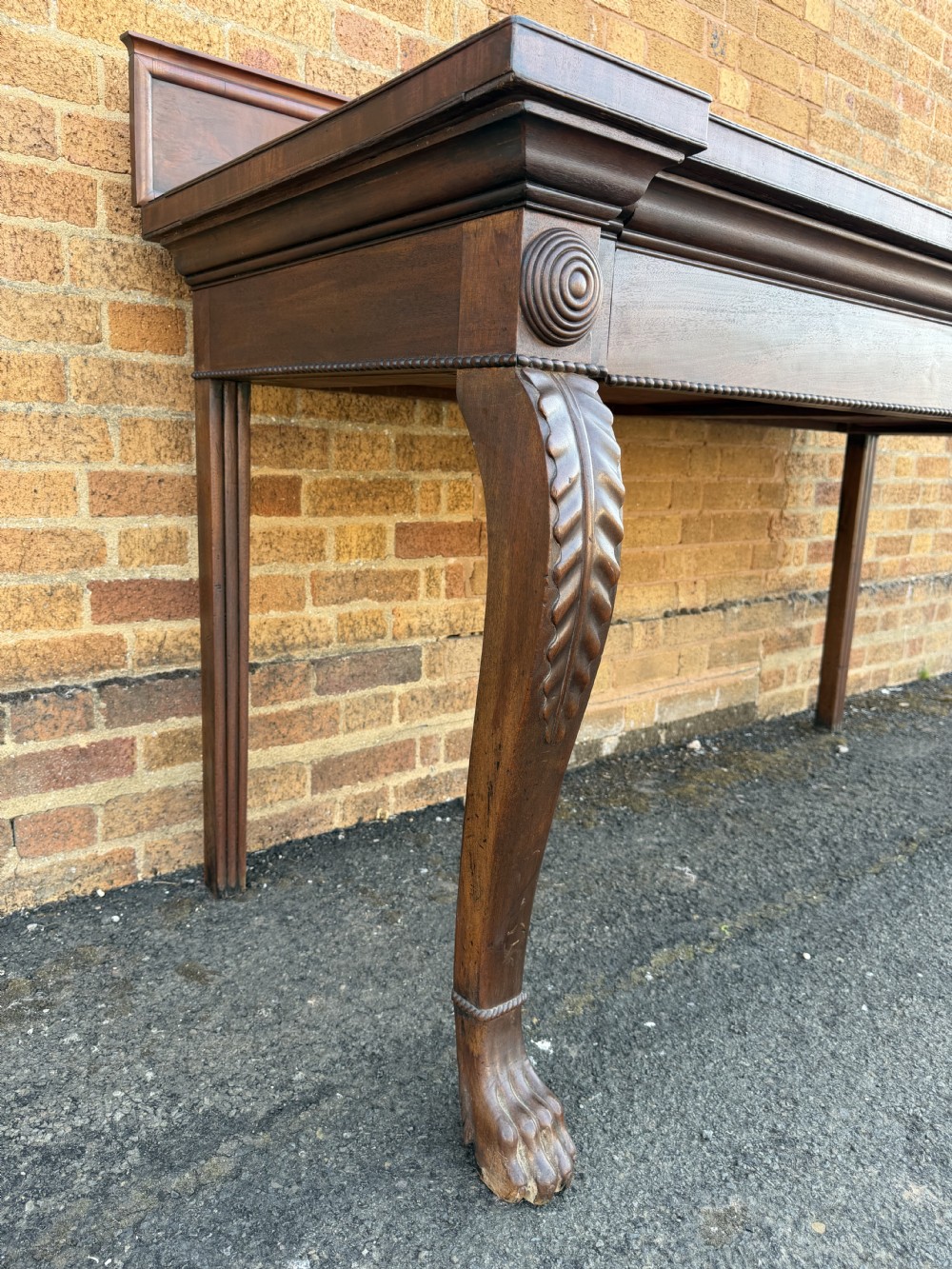 A large early 19th-century George IV mahogany serving table featuring a raised gallery back with carved cresting, carved cabriole front legs, and lion paw feet. View VI