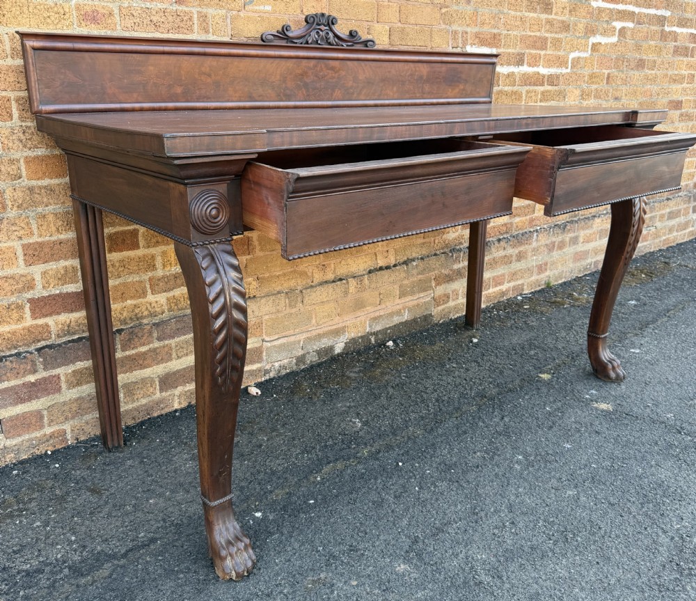 A large early 19th-century George IV mahogany serving table featuring a raised gallery back with carved cresting, carved cabriole front legs, and lion paw feet. View IX