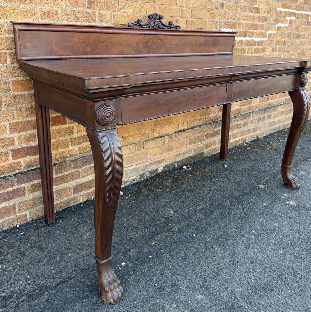A large early 19th-century George IV mahogany serving table featuring a raised gallery back with carved cresting, carved cabriole front legs, and lion paw feet. View XIII