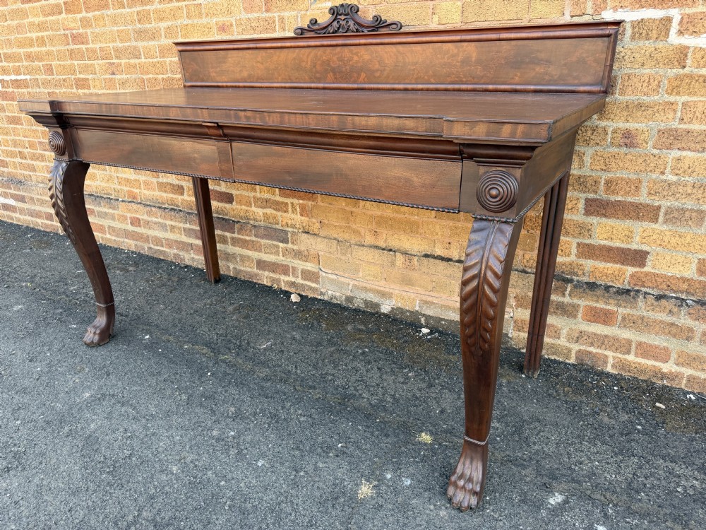 A large early 19th-century George IV mahogany serving table featuring a raised gallery back with carved cresting, carved cabriole front legs, and lion paw feet. View XX