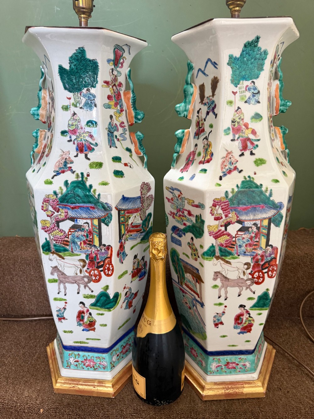 A pair of hexagonal Chinese famille-verte porcelain lamps decorated with figures in traditional scenes and set on gilded bases. View XV