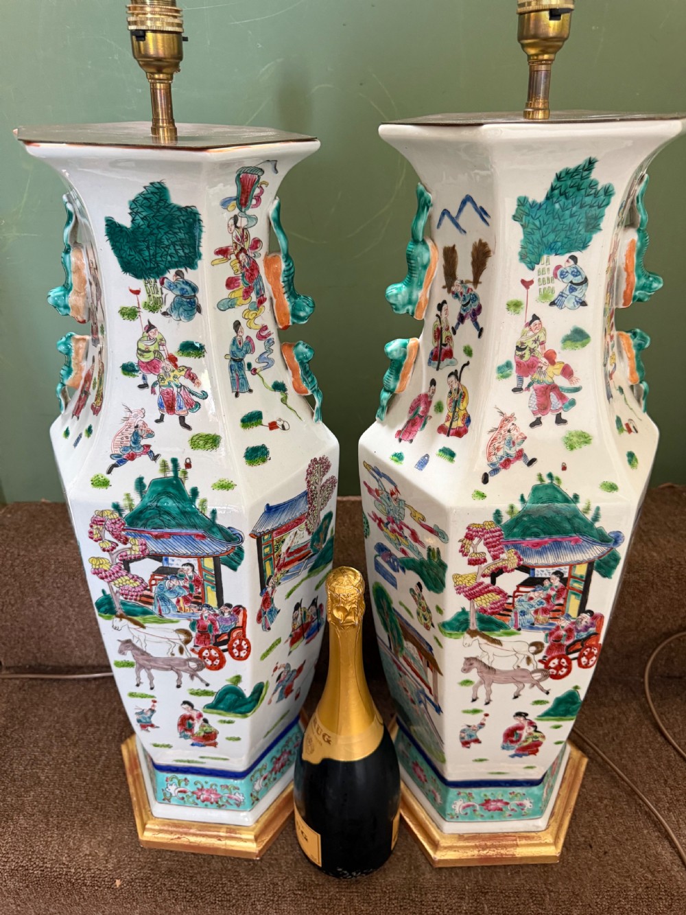 A pair of hexagonal Chinese famille-verte porcelain lamps decorated with figures in traditional scenes and set on gilded bases. View XVI