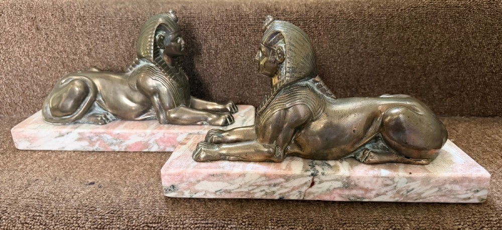 A pair of bronze recumbent sphinx sculptures featuring detailed Nemes headdresses mounted on rectangular pink marble bases. View II