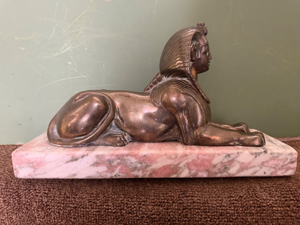 A pair of bronze recumbent sphinx sculptures featuring detailed Nemes headdresses mounted on rectangular pink marble bases. View XI