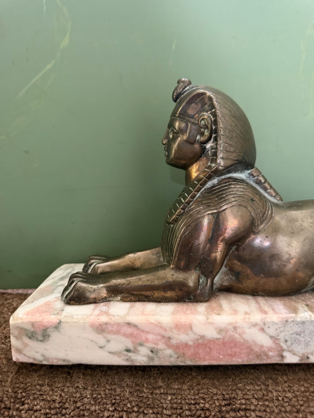 A pair of bronze recumbent sphinx sculptures featuring detailed Nemes headdresses mounted on rectangular pink marble bases. View XIII
