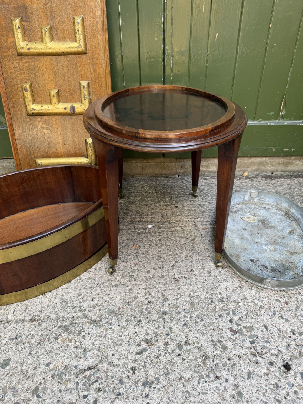 An 18th-century George III mahogany oval wine cooler with thick brass bands and brass handles, resting on a four-legged tapered stand with castors. View VII