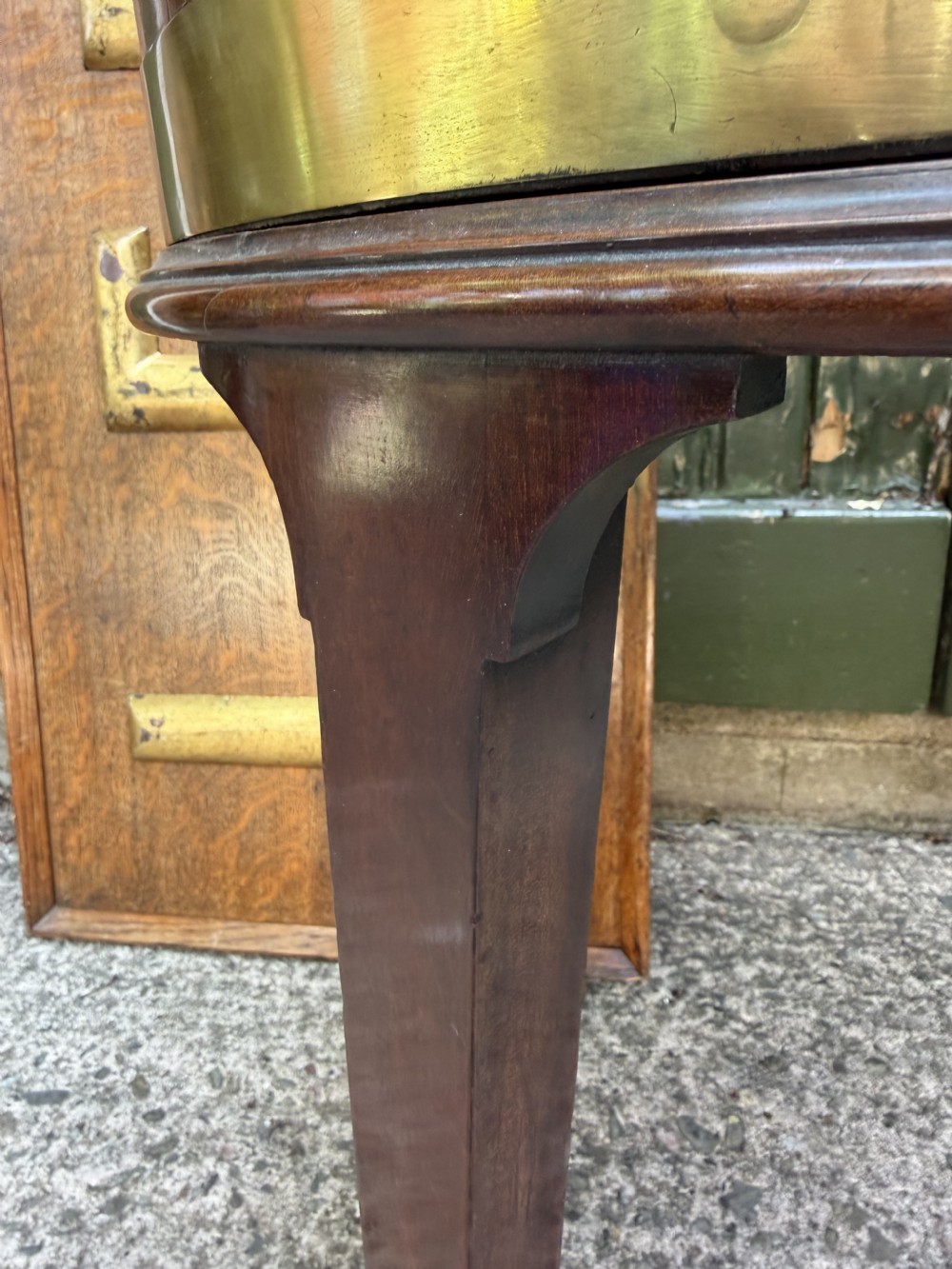 An 18th-century George III mahogany oval wine cooler with thick brass bands and brass handles, resting on a four-legged tapered stand with castors. View XVI