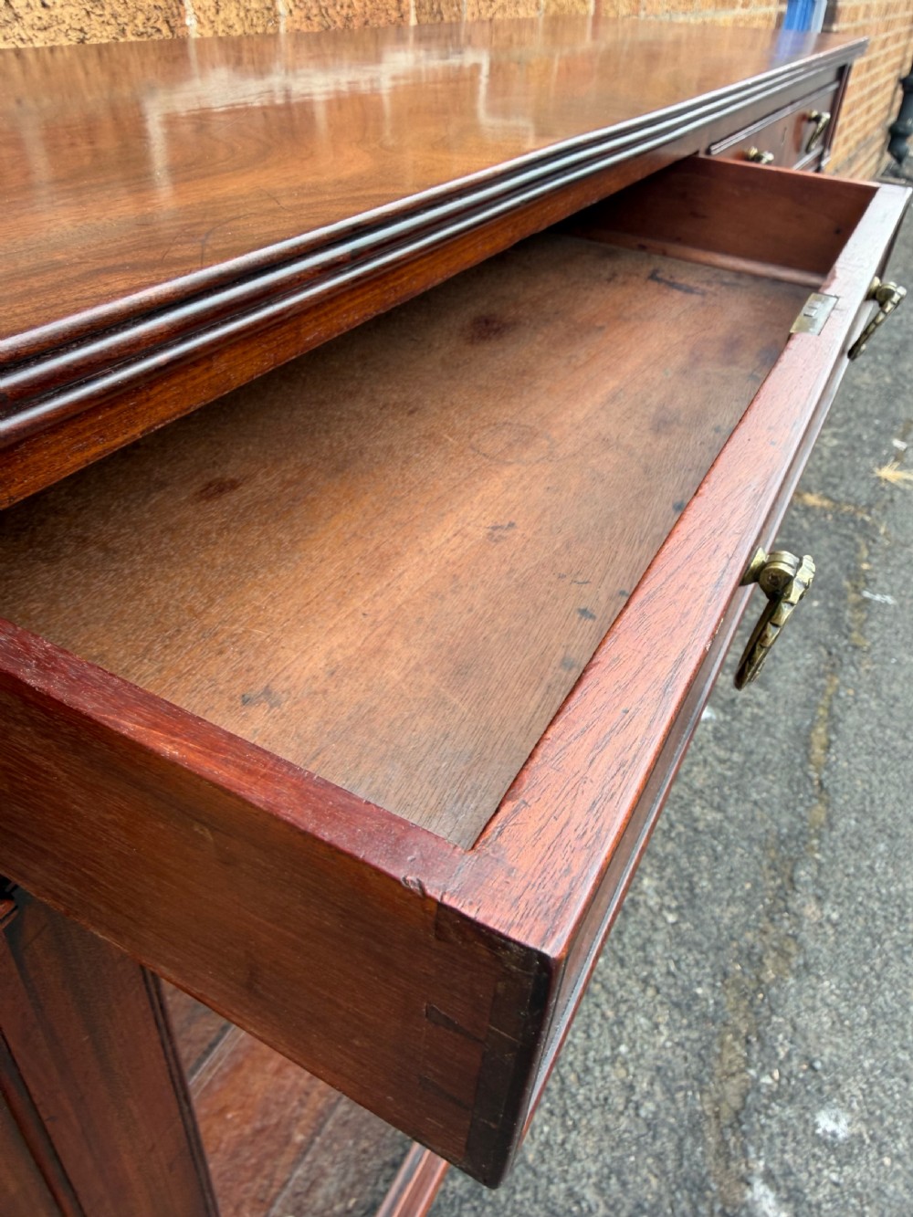 An early nineteenth-century George III mahogany low bookcase featuring two top frieze drawers over glazed twin doors and turned feet. View V