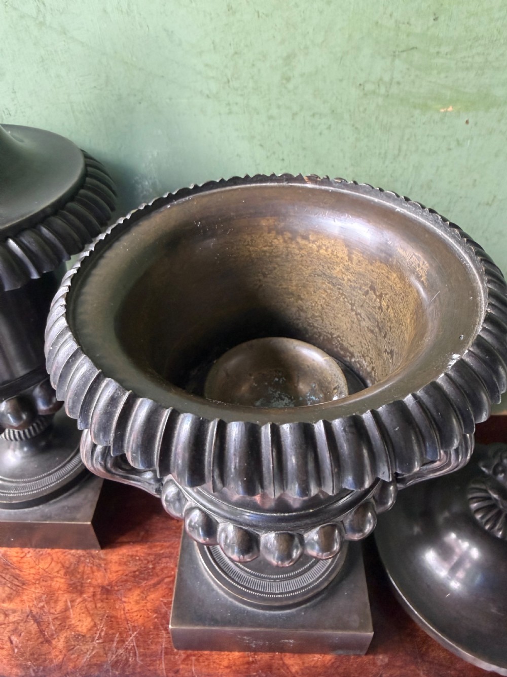 A pair of Regency patinated bronze campana-shaped cassolettes with gadrooned bodies, twin handles, pinecone finials, and square bases. View IV