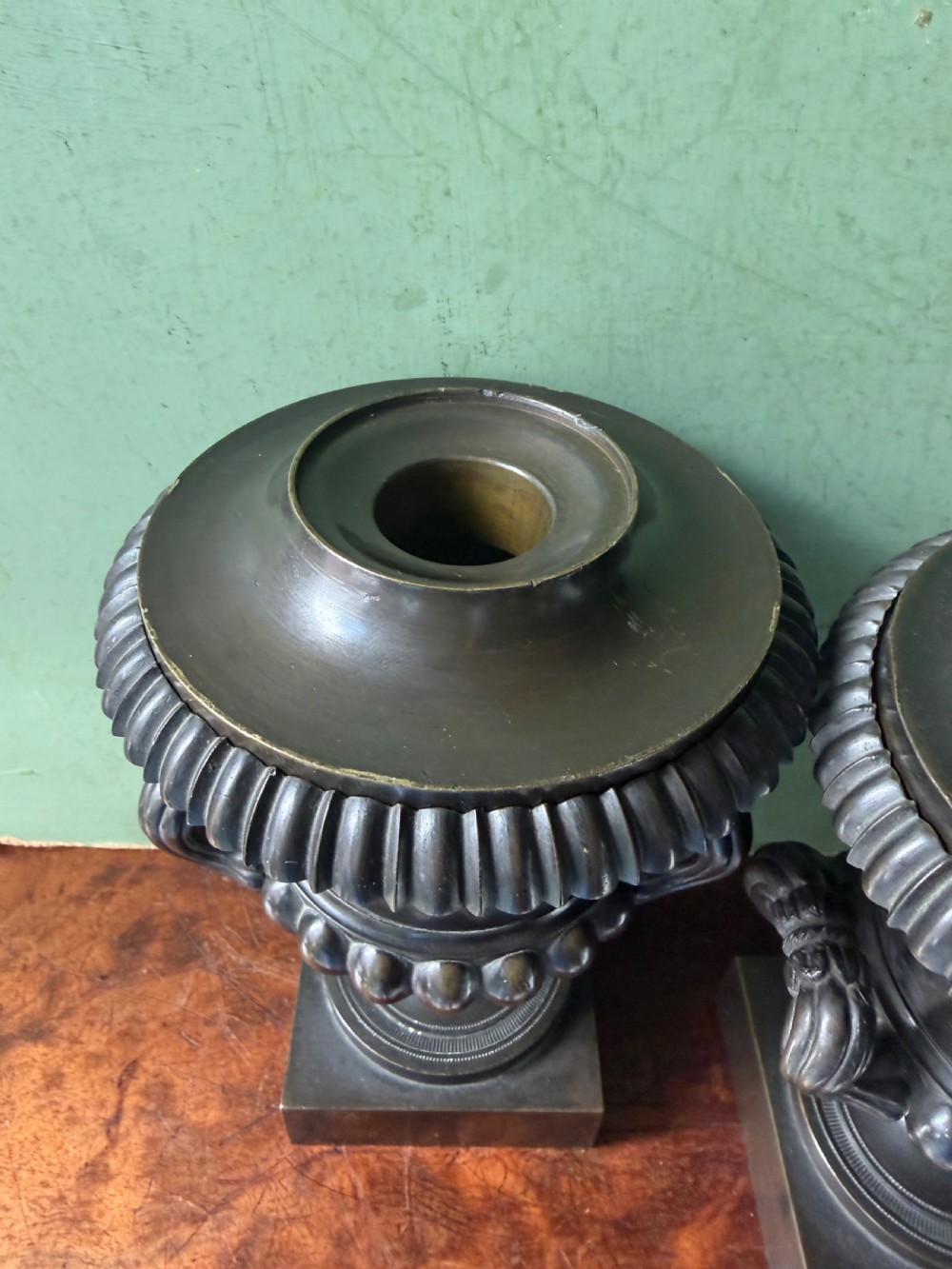 A pair of Regency patinated bronze campana-shaped cassolettes with gadrooned bodies, twin handles, pinecone finials, and square bases. View V