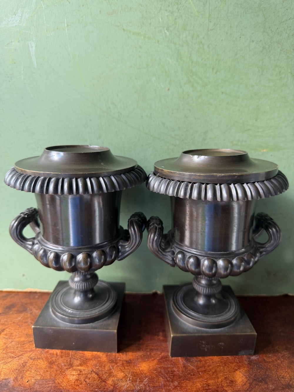 A pair of Regency patinated bronze campana-shaped cassolettes with gadrooned bodies, twin handles, pinecone finials, and square bases. View VI