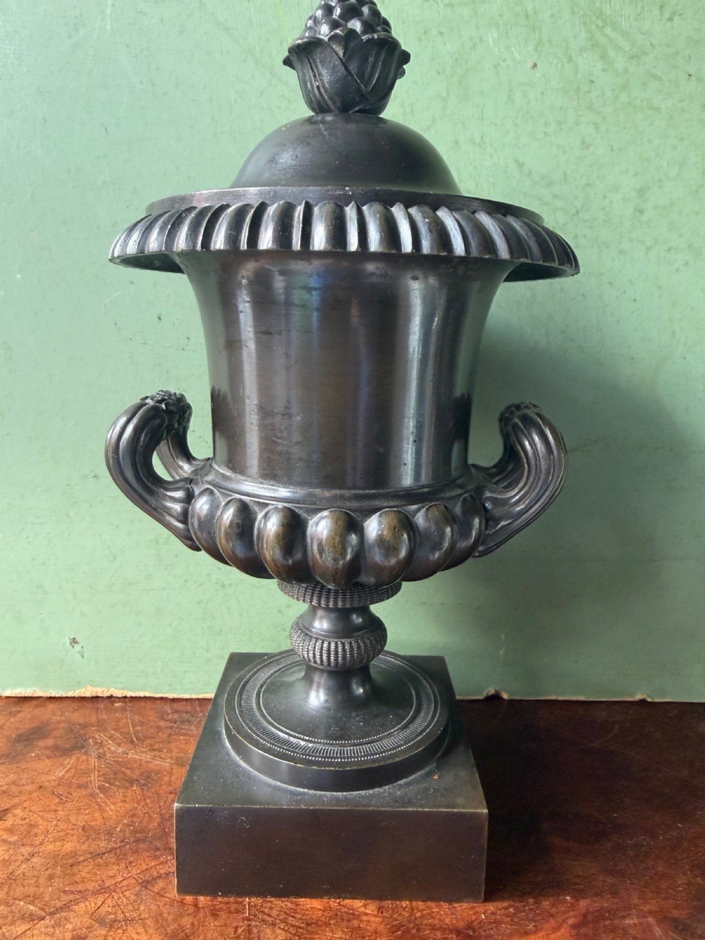 A pair of Regency patinated bronze campana-shaped cassolettes with gadrooned bodies, twin handles, pinecone finials, and square bases. View XII