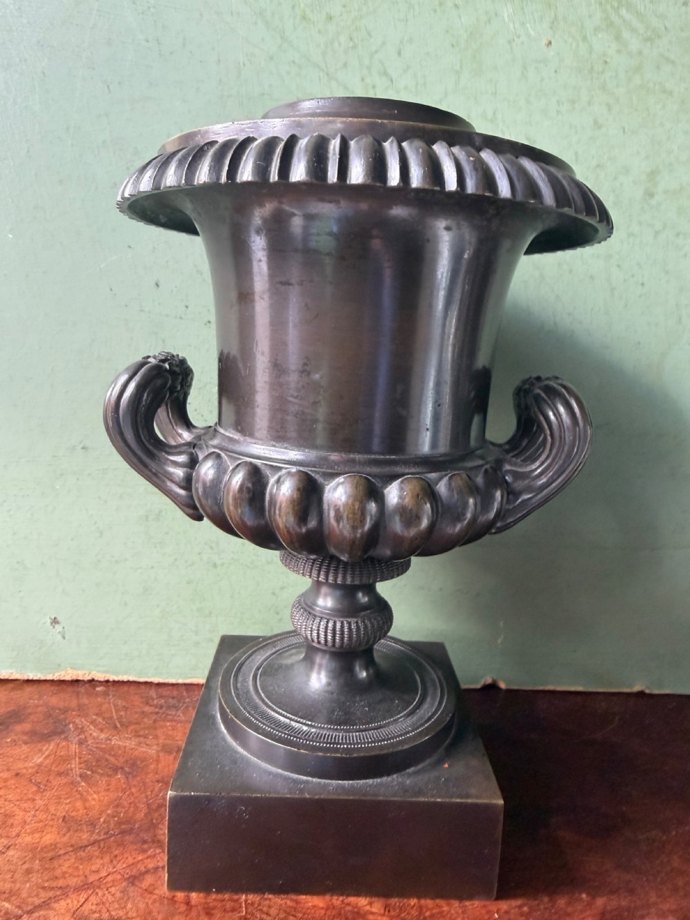 A pair of Regency patinated bronze campana-shaped cassolettes with gadrooned bodies, twin handles, pinecone finials, and square bases. View XV