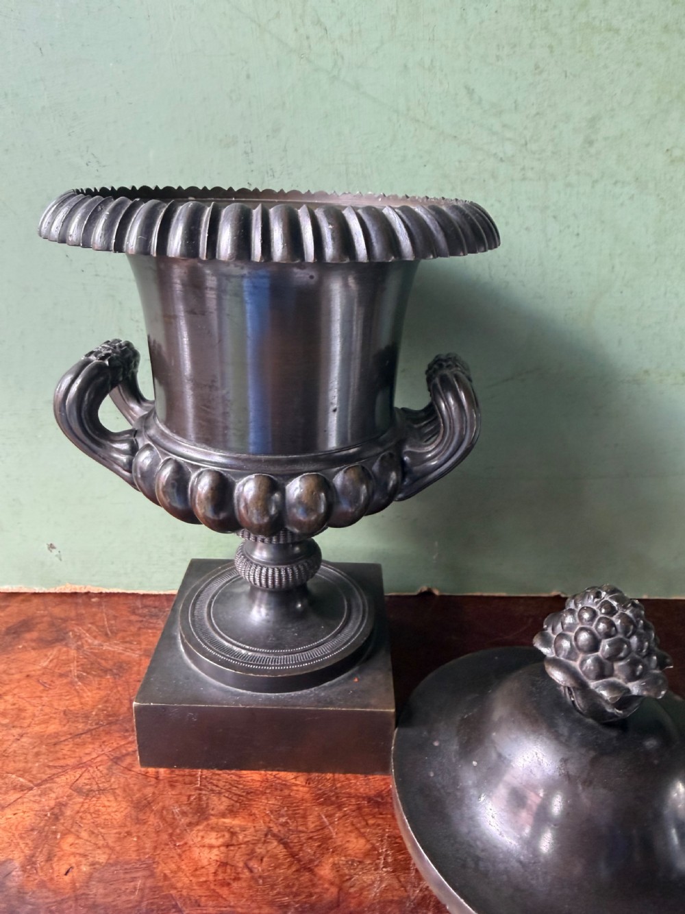 A pair of Regency patinated bronze campana-shaped cassolettes with gadrooned bodies, twin handles, pinecone finials, and square bases. View XVI