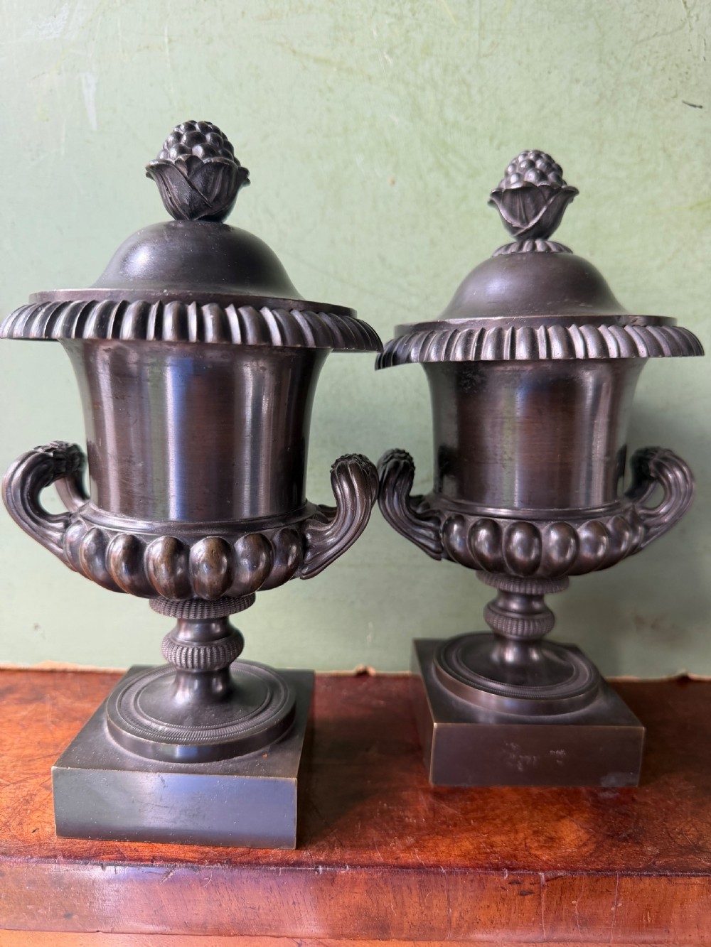 A pair of Regency patinated bronze campana-shaped cassolettes with gadrooned bodies, twin handles, pinecone finials, and square bases. View XVIII