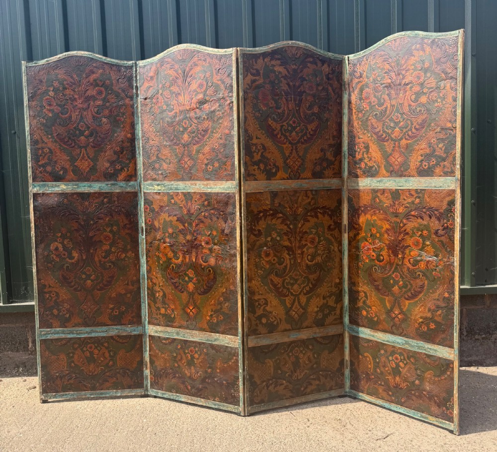 A late nineteenth-century four-fold canvas room screen featuring polychrome floral and scroll decoration in warm brown and green tones with serpentine cresting.