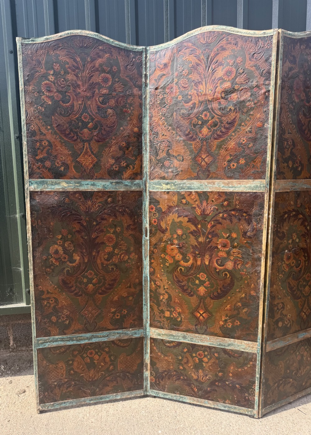 A late nineteenth-century four-fold canvas room screen featuring polychrome floral and scroll decoration in warm brown and green tones with serpentine cresting. View V
