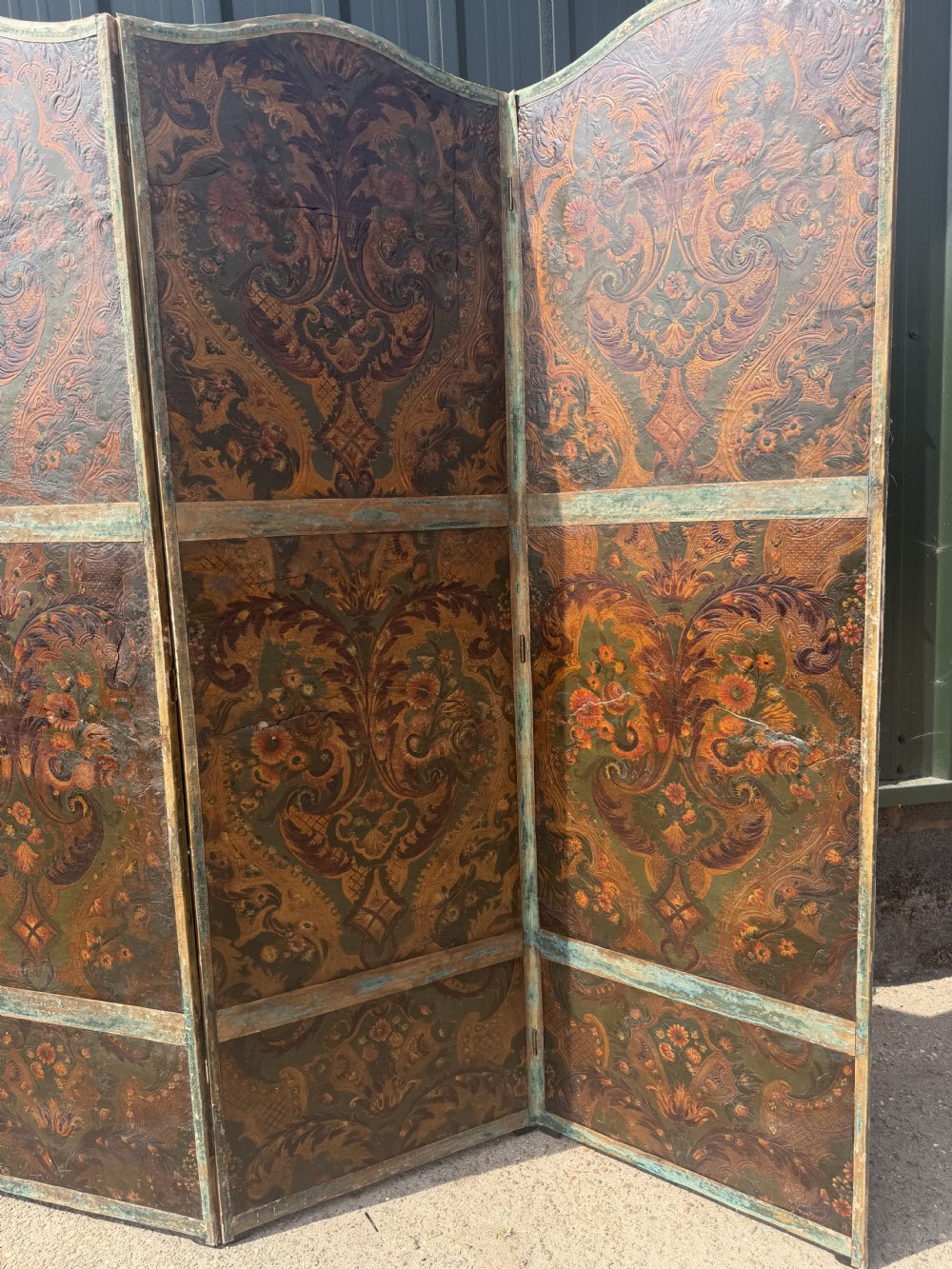 A late nineteenth-century four-fold canvas room screen featuring polychrome floral and scroll decoration in warm brown and green tones with serpentine cresting. View VI