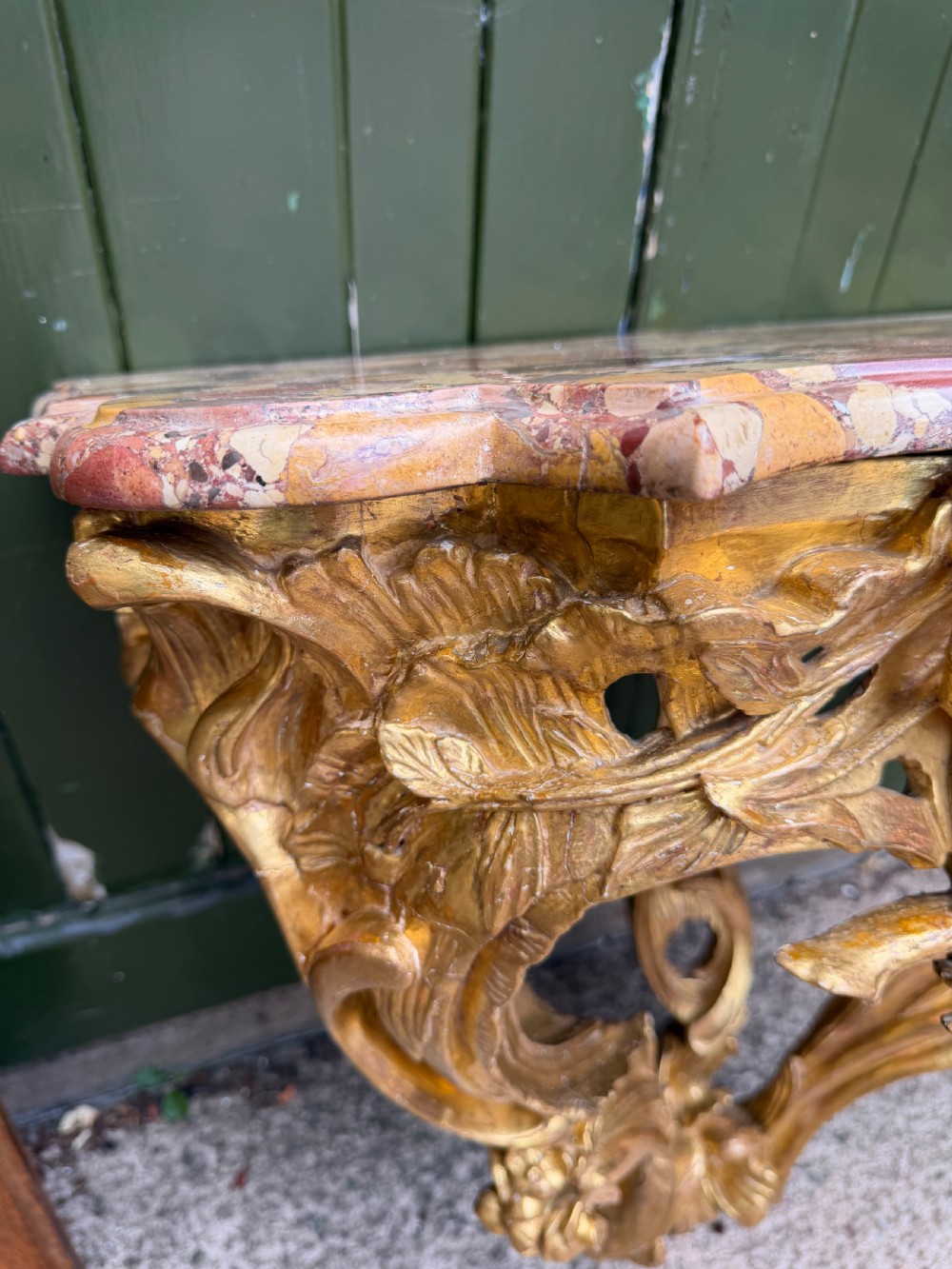 An 18th-century style French carved giltwood wall console table featuring intricate foliage, a central bird motif, and a variegated pink and ochre Breche dAlep marble top. View V