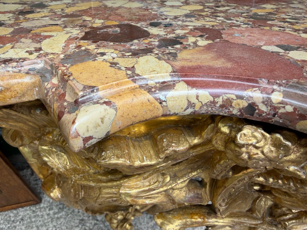 An 18th-century style French carved giltwood wall console table featuring intricate foliage, a central bird motif, and a variegated pink and ochre Breche dAlep marble top. View XI