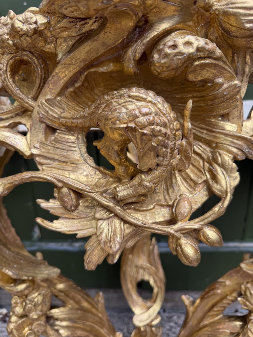 An 18th-century style French carved giltwood wall console table featuring intricate foliage, a central bird motif, and a variegated pink and ochre Breche dAlep marble top. View XVI