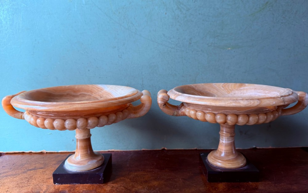 A pair of 19th-century carved amber alabaster tazze with gadrooned rims and twin loop handles set on square black marble plinths. View II