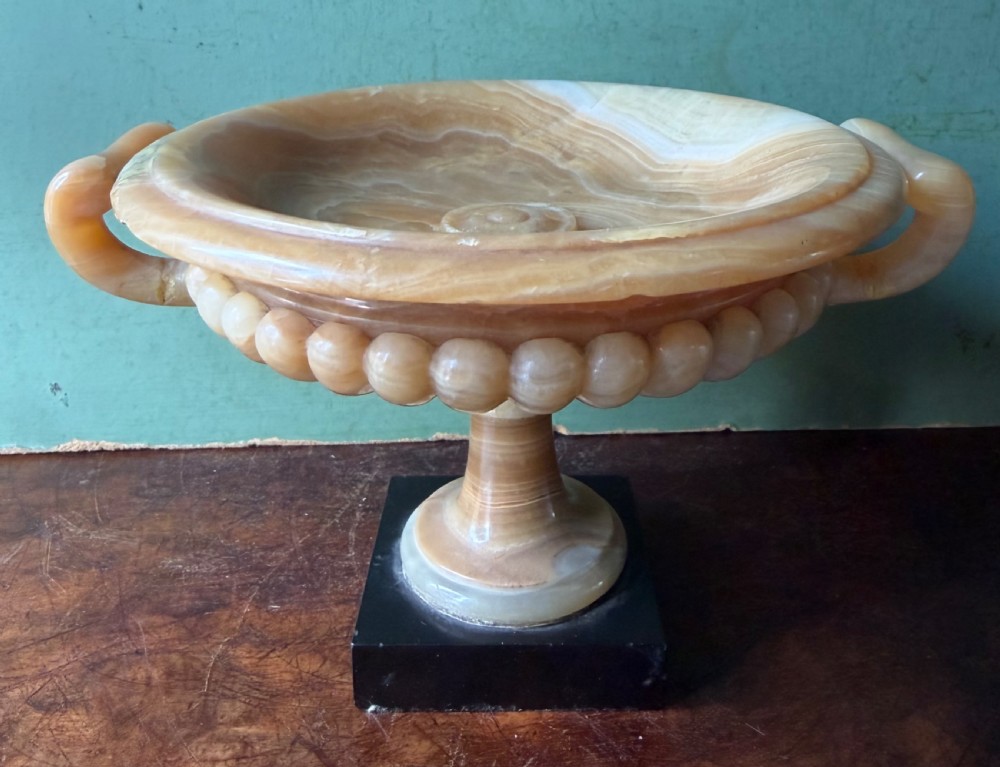 A pair of 19th-century carved amber alabaster tazze with gadrooned rims and twin loop handles set on square black marble plinths. View VIII