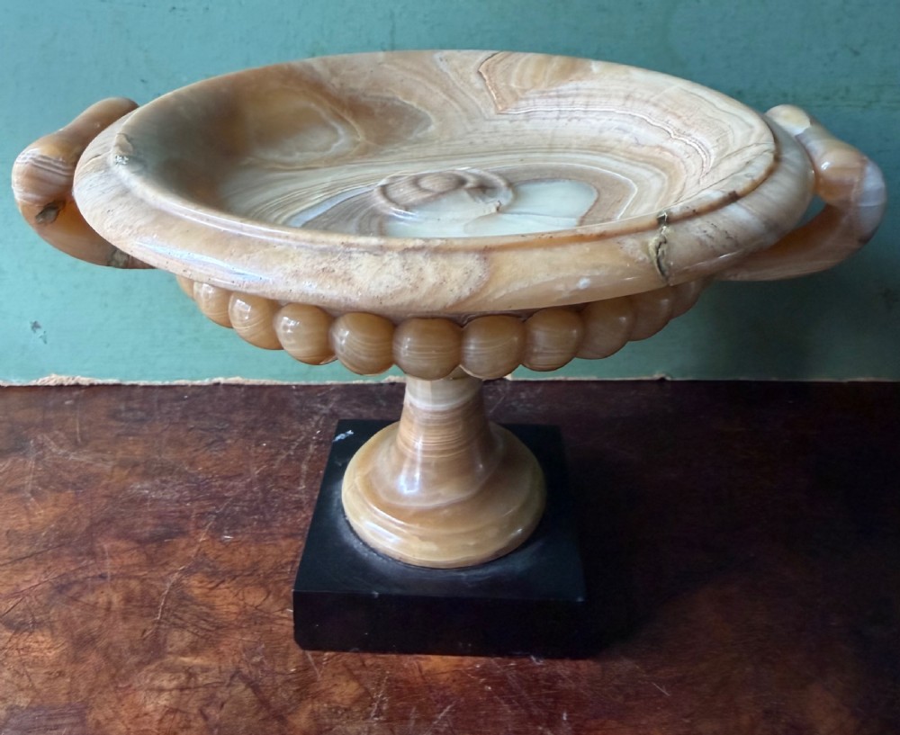 A pair of 19th-century carved amber alabaster tazze with gadrooned rims and twin loop handles set on square black marble plinths. View XI